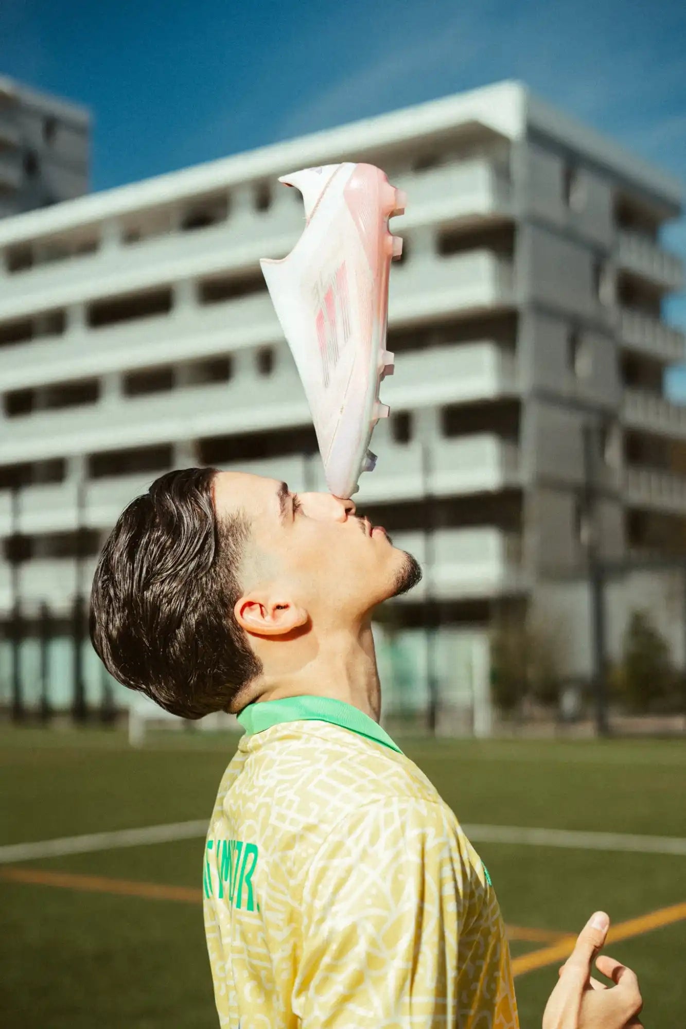 Une personne équilibre une chaussure de soccer blanche et rose sur son nez.